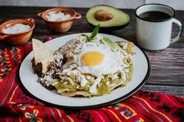 Mexican green chilaquiles with fried egg, chicken and spicy green sauce traditional breakfast in Mexico	
