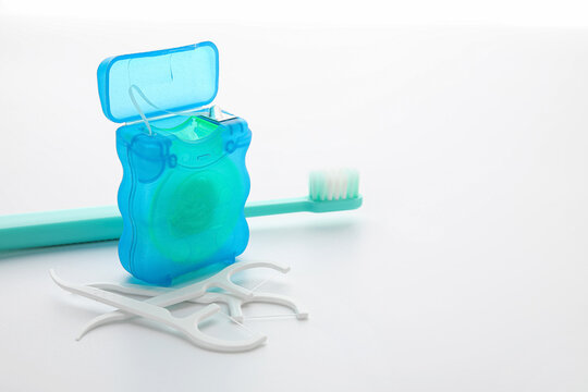 Dental floss with toothpicks and brush on white background
