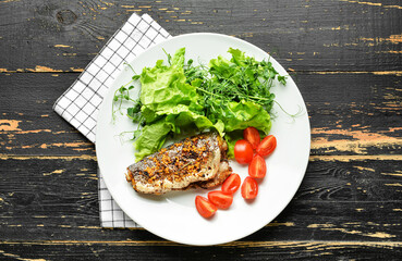 Plate with delicious sea bass fish and vegetables on dark wooden background