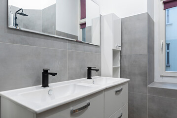 Double sink in bathroom. Ceramic washbasin in wasroom with grey tiles and mirror in stylish interior in hotel.