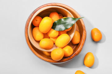 Bowl with tasty kumquat fruits on white background