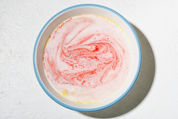 Bath bomb dissolving in bowl with water on white background