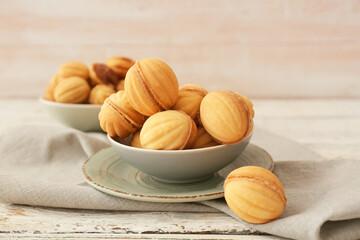 Bowls of tasty walnut shaped cookies with boiled condensed milk on wooden table
