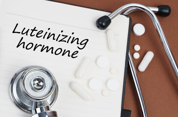 On a brown surface lie pills, a stethoscope and a notebook with the inscription - Luteinizing hormone