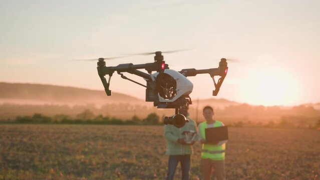 African and asian farm engineers using laptop digital tablet controlling application for automated flying drone. Farming activity, increasing productivity. Teamwork. Field landscape.