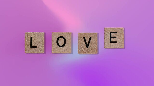 text - Love on Animated wooden blocks on trending purple multi colored animation background. High quality 4k motion design graphics art footage.Romantic concept for mother's, St. Valentine's postcard