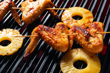 Tasty chicken wings skewers with pineapple slices on grill