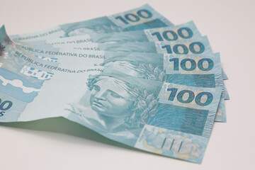Dinheiro de cem reais brasileiro na mão de uma pessoa segurando.
