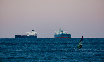 surfer in front of oil tanker ship