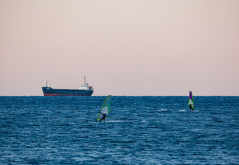 surfers in front of oil tanker ship