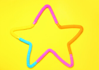 Star made of Pop Tubes on yellow background