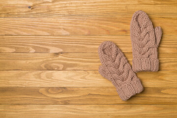 Brown winter mittens on wooden background. Top view