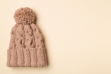 Brown winter hat with pompon on color background. Top view