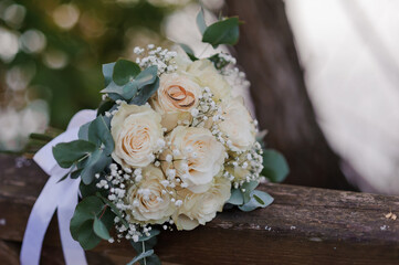 A pair of gold rings on a bouquet of white roses