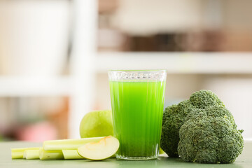 Glass of healthy green juice and fresh ingredients on table against blurred background