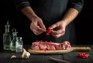 The professional chef prepares raw veal meat. Before baking cook puts the viburnum on the beef. National dish is being prepared in the restaurant kitchen
