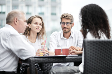 Fototapeta premium Smiling colleagues working together developing business strategy for their next project. Young casually dressed business people having discussion on sunny terrace. Modern job in comfortable conditions