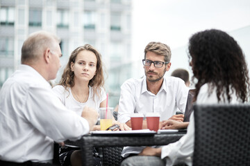 Smiling colleagues working together developing business strategy for their next project. Young casually dressed business people having discussion on sunny terrace. Modern job in comfortable conditions