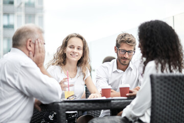 Smiling colleagues working together developing business strategy for their next project. Young casually dressed business people having discussion on sunny terrace. Modern job in comfortable conditions