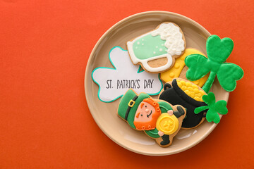 Plate with tasty gingerbread cookies for St. Patrick's Day celebration on color background