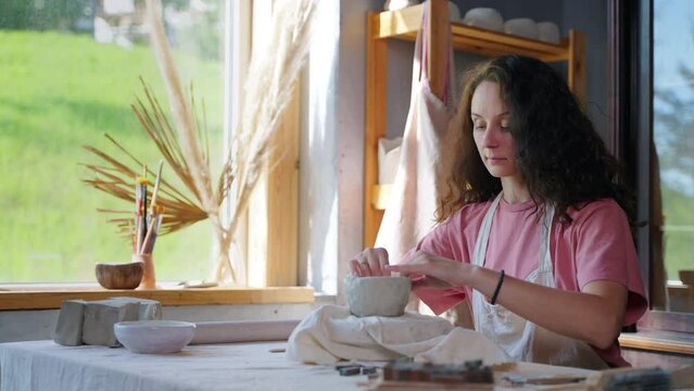 adult woman is making ceramic cup in pottery workshop