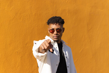 Young african american man wearing sunglasses pointing displeased and frustrated to the camera,...