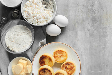 Plate with tasty cottage cheese pancakes and ingredients on grey background