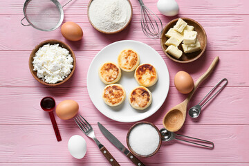 Plate with tasty cottage cheese pancakes and ingredients on pink wooden background