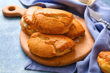 Wooden board of tasty sochniki with cottage cheese on blue background