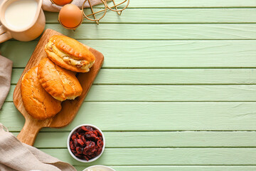 Board of tasty sochniki with cottage cheese on green wooden background