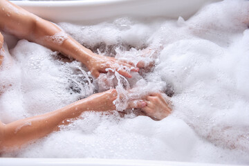 Close up top view of the hands of a couple in love taking a bath together with white foam. Lovers shake the water with soap to form foam. Newlyweds have fun on honeymoon weekend morning. Hand hygiene