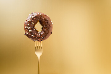 Fork stuck into a donut with a gold background