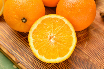 Wooden board with fresh oranges on green background, closeup