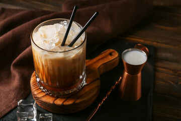 Glass of White Russian cocktail on wooden background