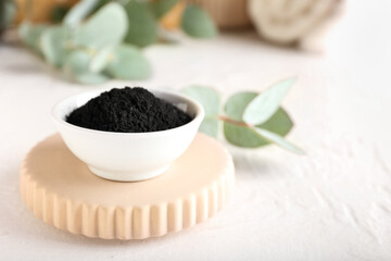 Bowl with activated charcoal tooth powder on white background