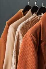 Various clothes, cashmere sweaters, coats, corduroy jacket on hangers close-up. Stylish capsule wardrobe. Classic women's fashion clothes.