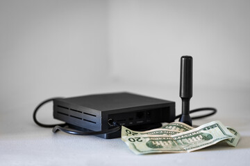 HNT cryptocurrency miner hotspot with antenna for radio connection and dollar bills as an association with the profit from mining