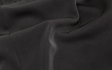 Black satin soft fabric. Soft focus texture of silk background. Crumpled dark grey color wavy...