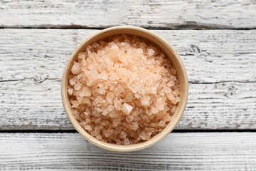 Bowl of sea salt on light wooden background