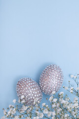 Glamorous Easter eggs with flowers. Copy Space. Cheerful table decorations for the spring holiday. Fashion minimal concept