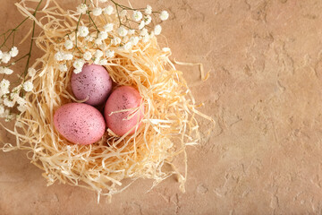 Nest with beautiful Easter eggs and gypsophila flowers on color background