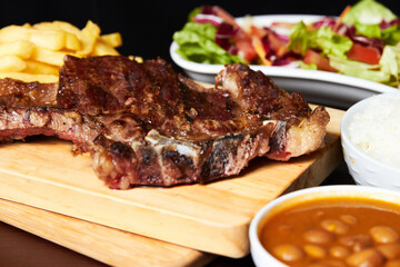 variety of meats with french fries, salad and rice with vegetable stew