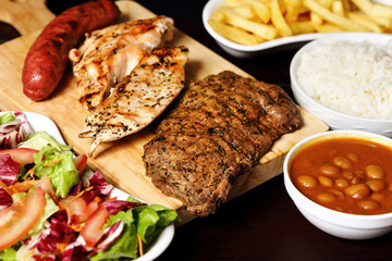 variety of meats with french fries, salad and rice with vegetable stew
