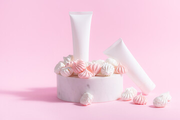 Obraz na płótnie Canvas Creative composition with two white unbranded cosmetic tubes on the podium with merengue cookies on light pink background. Cosmetic branding banner concept.