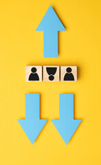 Wooden cubes with arrows in opposite directions on a yellow background. Concept of thinking...