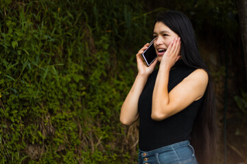 Una mujer latina emocionada  con un teléfono inteligente y lee buenas noticias, se siente feliz, se ve encantada y recibió una oferta increíble. Ganó la lotería, consiguió el trabajo soñado, celebre e