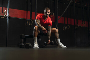 Chico musculoso con camiseta roja practicando deporte en un gym