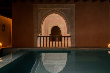 Hot water bath in darkness with reflection on the surface of the Arab arch with filigree and with a...