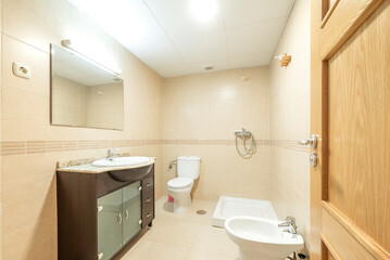 Fototapeta na wymiar Conventional toilet with dark wood furniture, veined marble countertop and white earthenware toilets