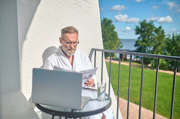 Focused gentleman in spectacles reading hot news at the table